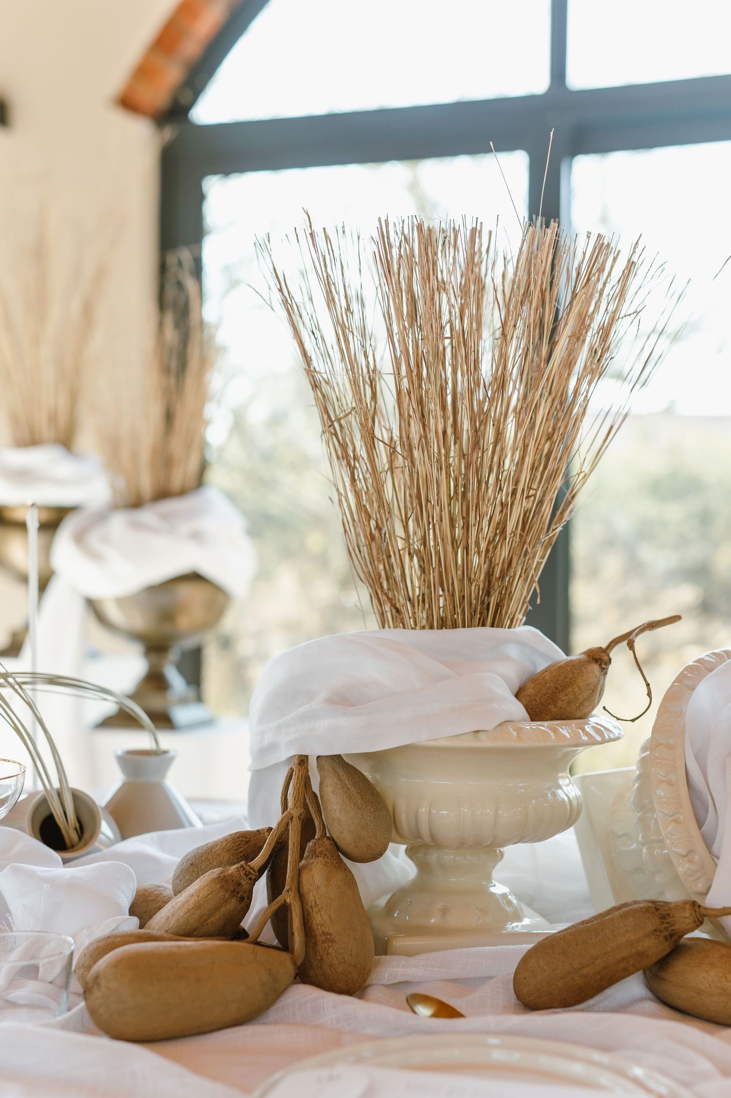 Wedding reception table decorated with dried wheat bundles and natural elements.