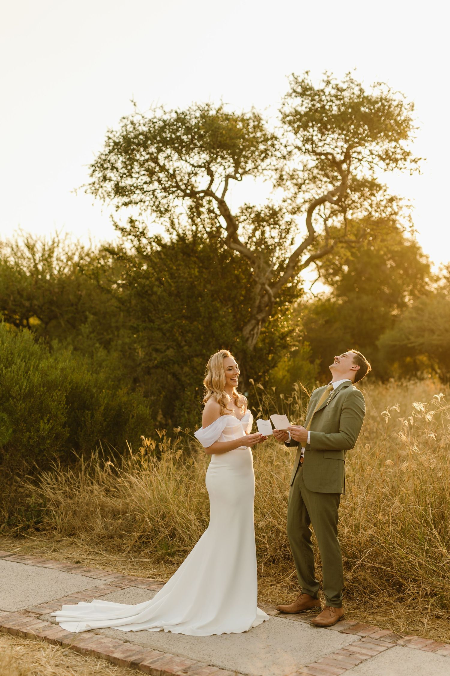 Wedding couple exchanging vows on a nature path during sunset with trees in the background.