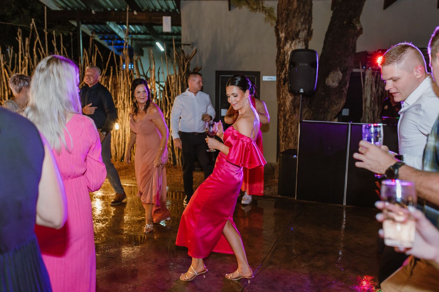 Woman in red dress dancing energetically on wedding reception dance floor surrounded by guests.