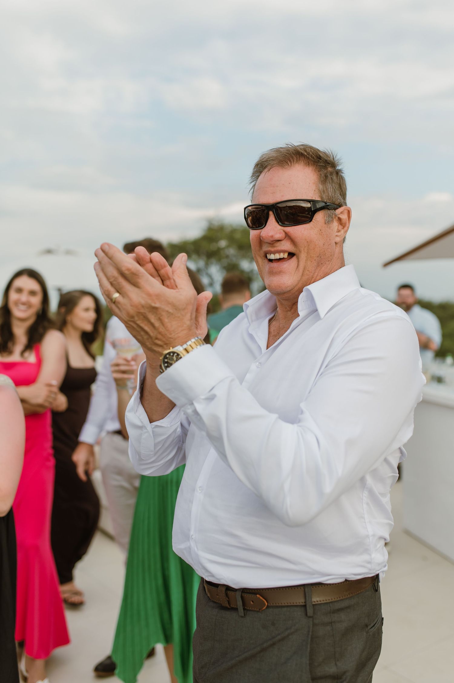 A joyful moment captured at an outdoor wedding celebration with guests in colorful dresses and white shirts dancing.