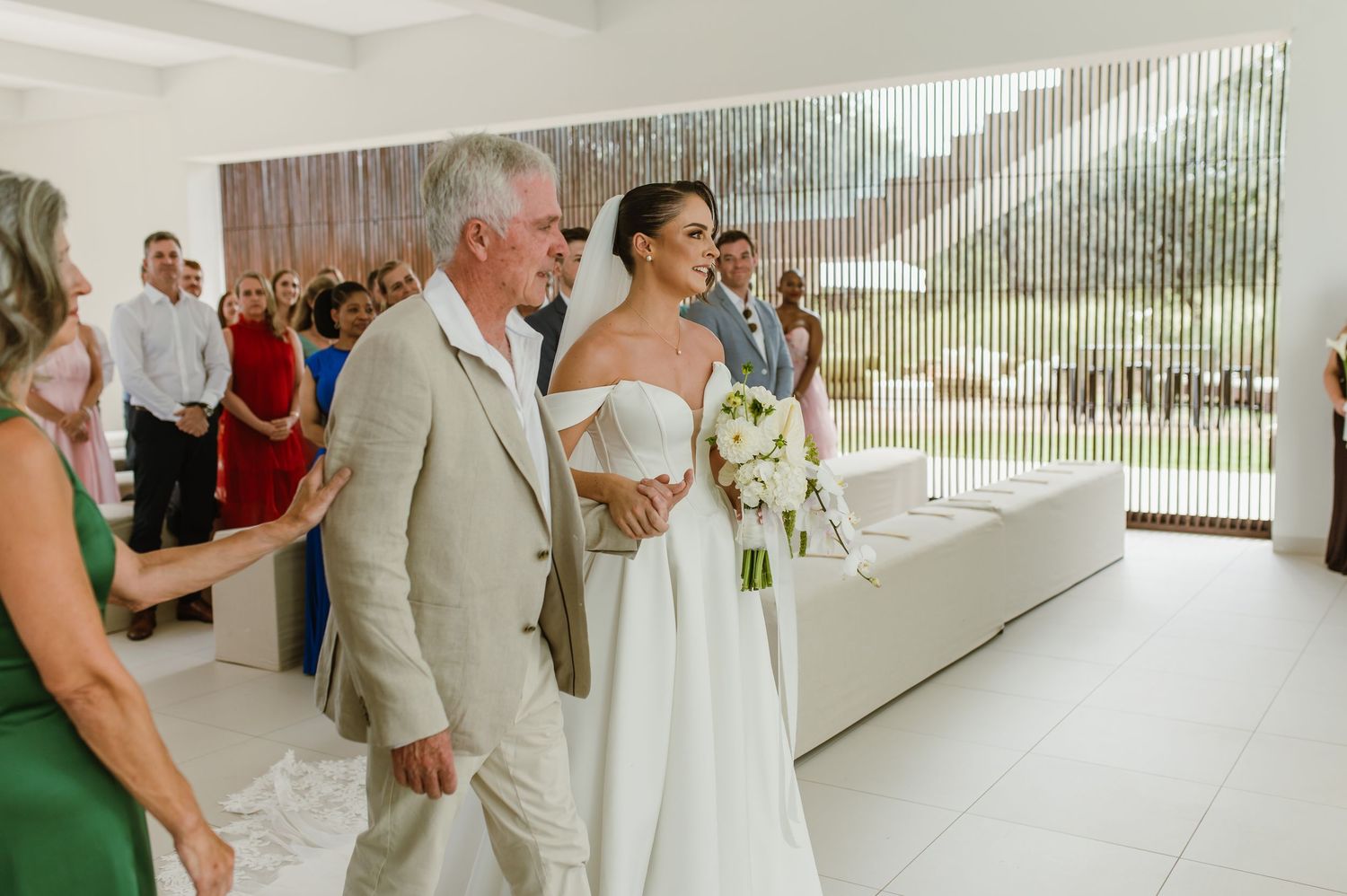 Elegant wedding ceremony taking place in a bright white contemporary space with natural light streaming in.