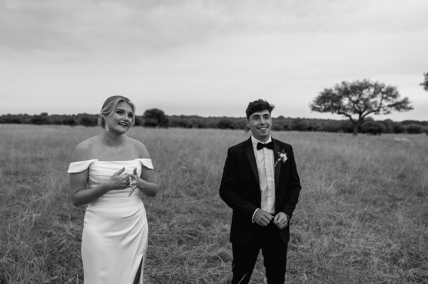 Black and white photo of wedding party celebrating in an open field.