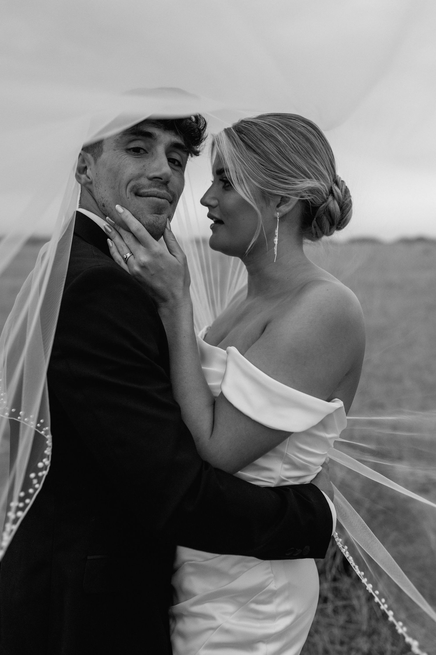 Black and white wedding photo captures joyful laughter between couple.