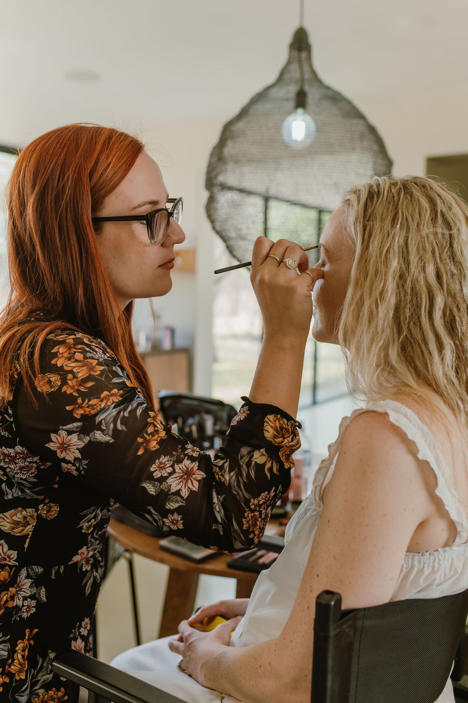 Behind-the-scenes preparation moment with makeup application in natural lighting.