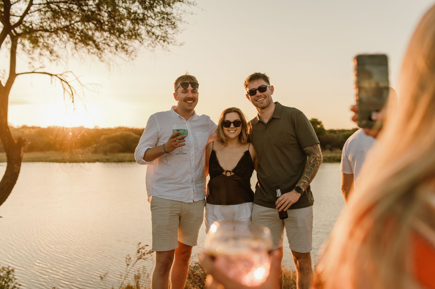 Group enjoying a sunset gathering by the lake with warm golden lighting.