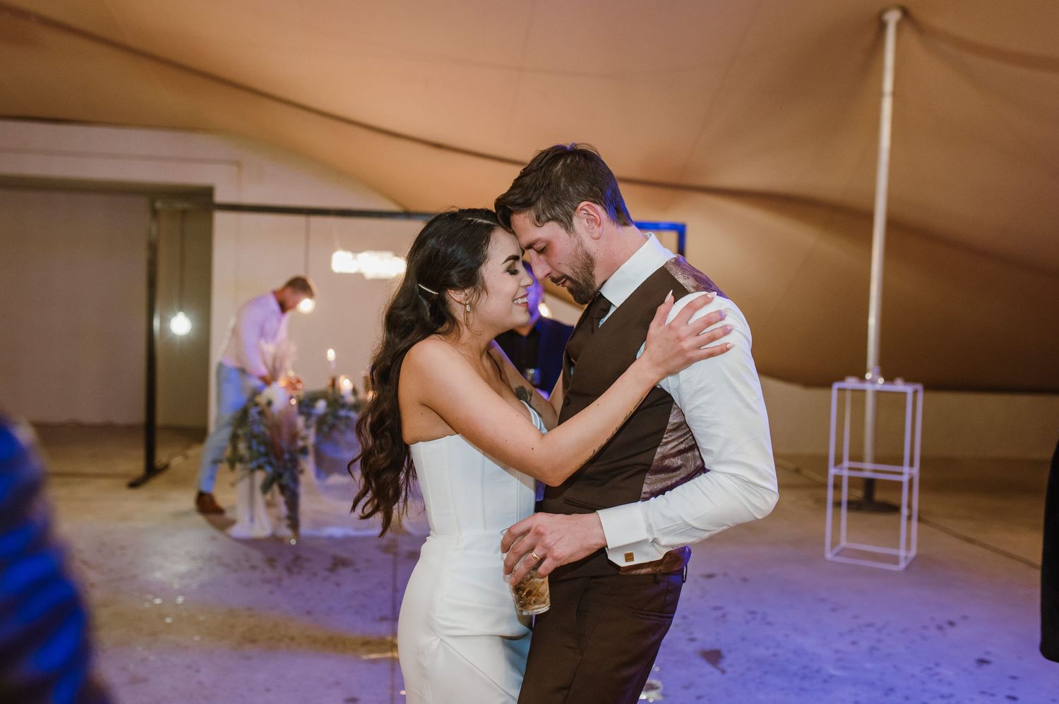 Romantic first dance moment at a tent wedding reception with ambient lighting.