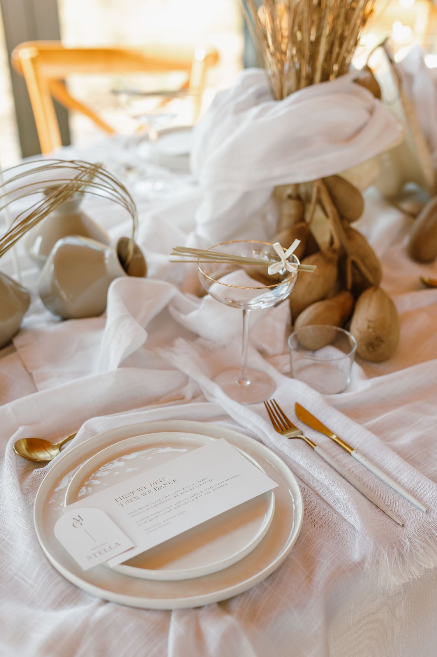 Minimalist white place settings with dried wheat centerpieces on elegant wedding reception tables.