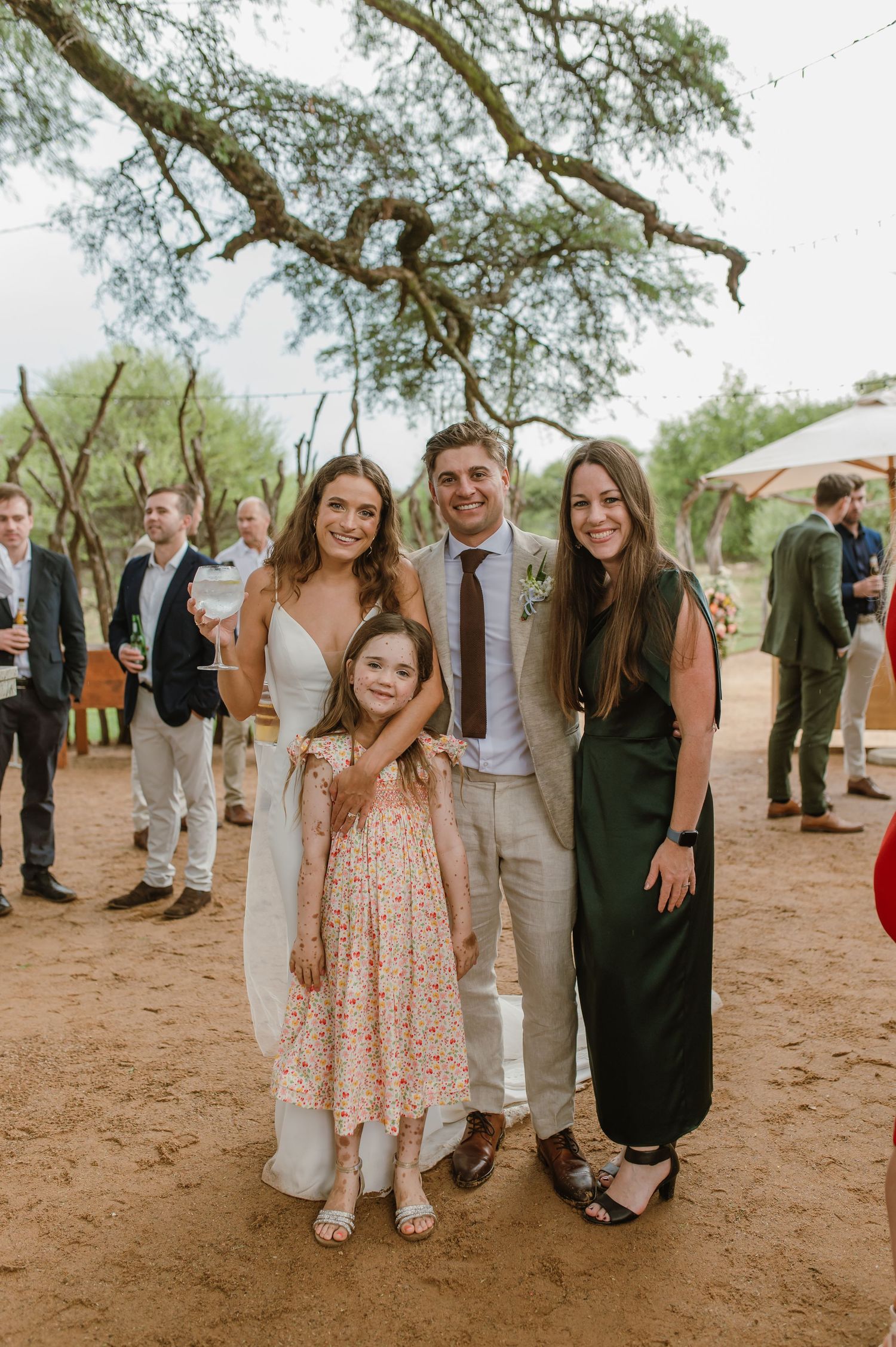 Outdoor celebration with guests gathered under trees at a casual event.