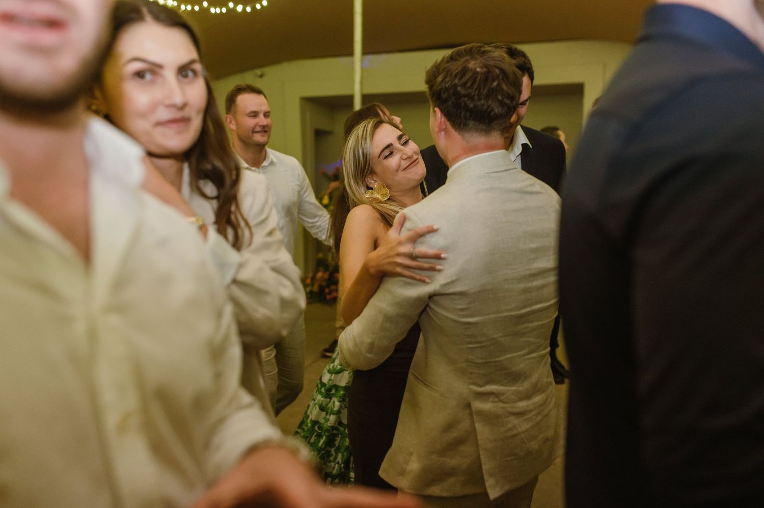 Candid moment of wedding guests mingling and dancing at an indoor reception venue.