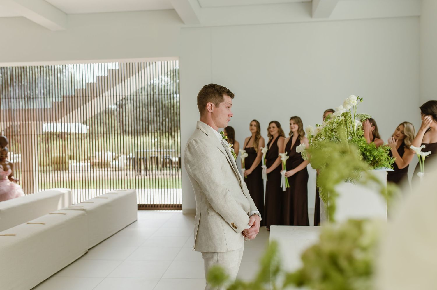Wedding ceremony setup in a modern white interior space with large windows.