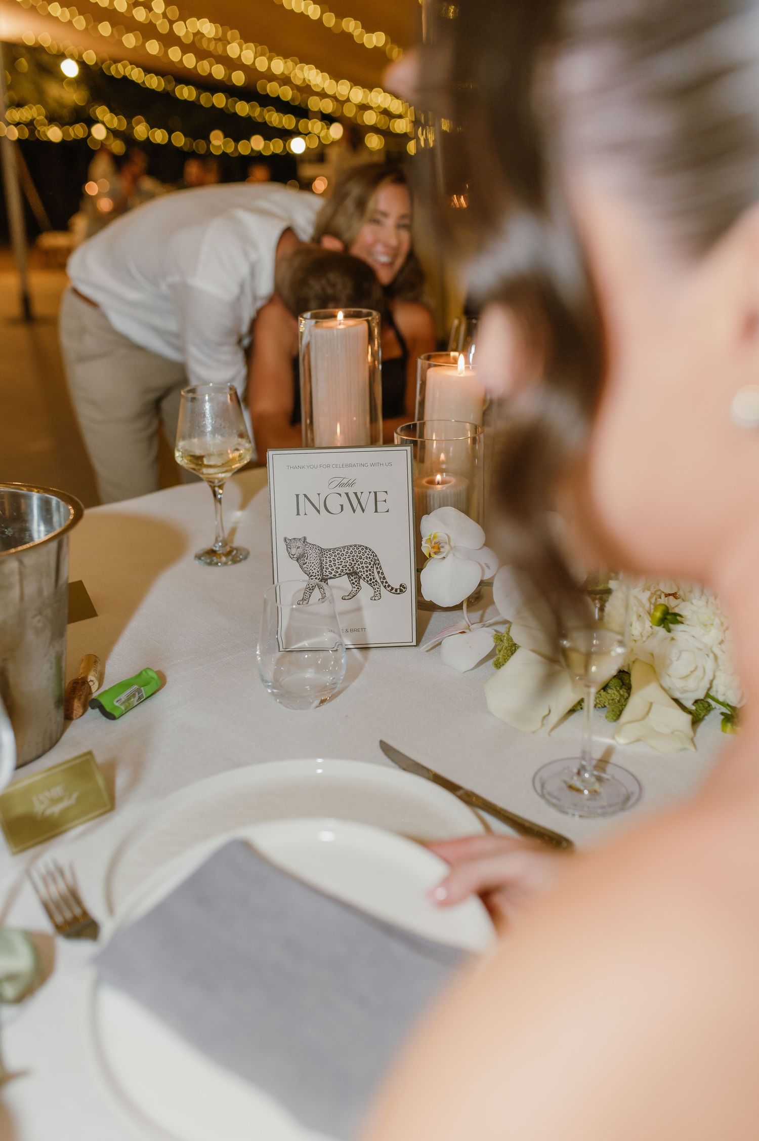 Wedding reception table details with white floral centerpieces, place settings, and table name cards in elegant decor.