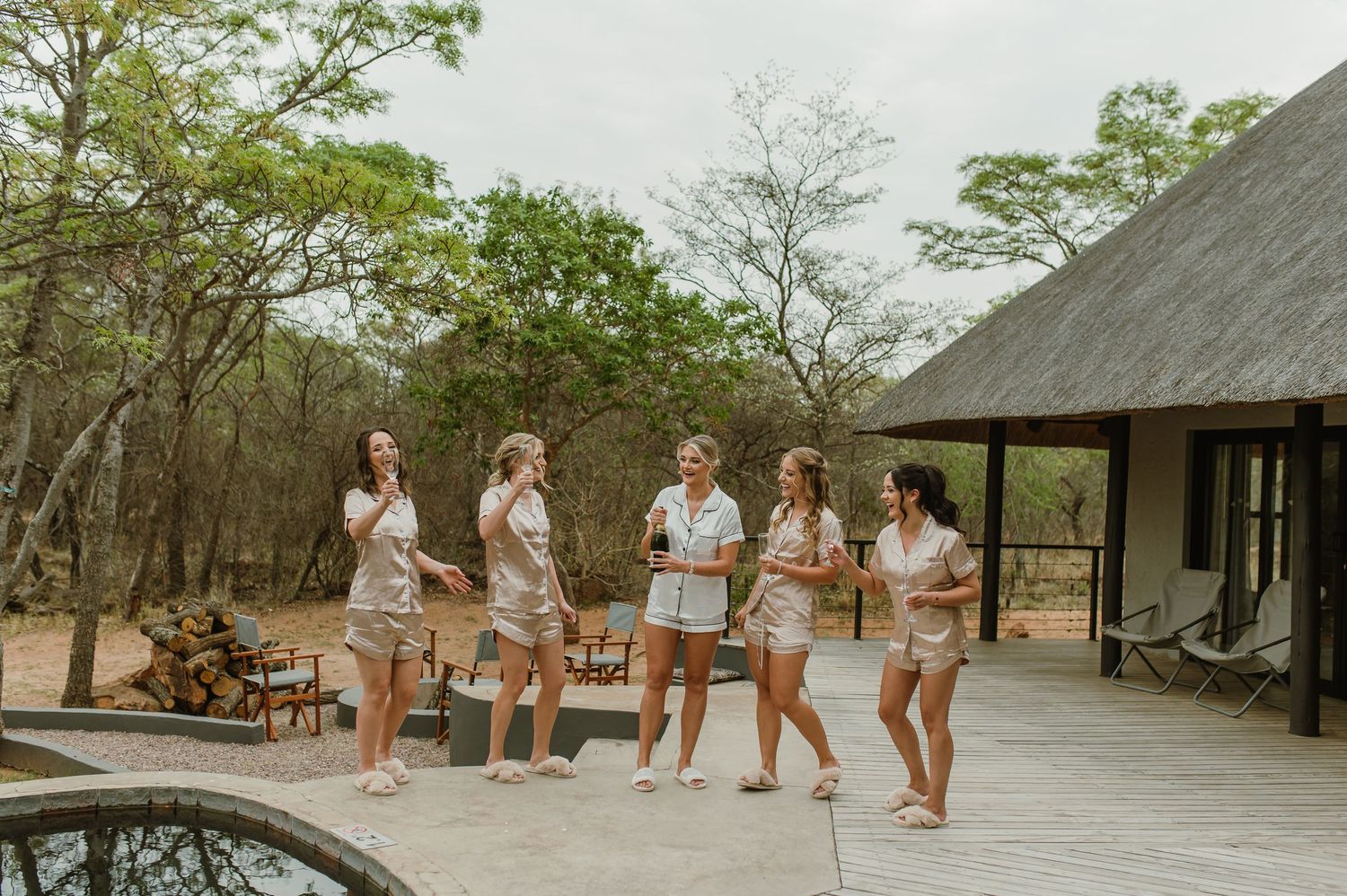 Outdoor group photo sequence with matching outfits near thatched roof buildings.