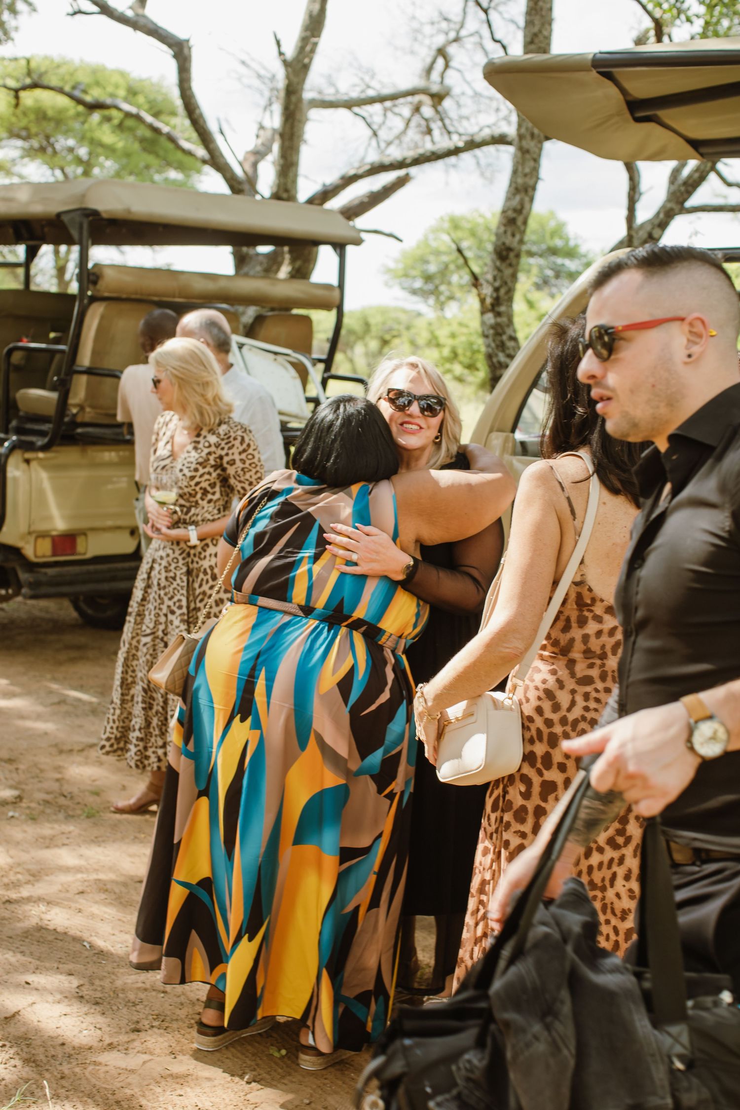 Wedding guests gathered around safari vehicles during an outdoor celebration.