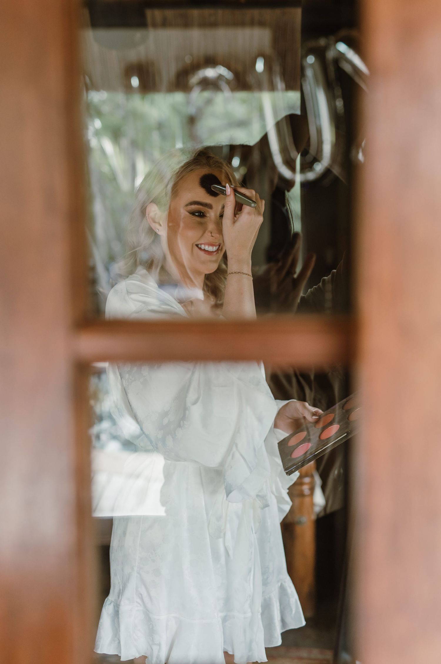 Wedding preparation moments captured through window reflections.