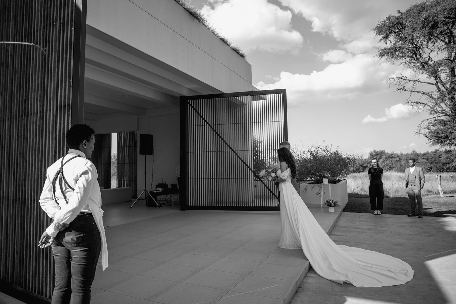 Modern architectural wedding venue exterior with dramatic vertical lines against blue sky.