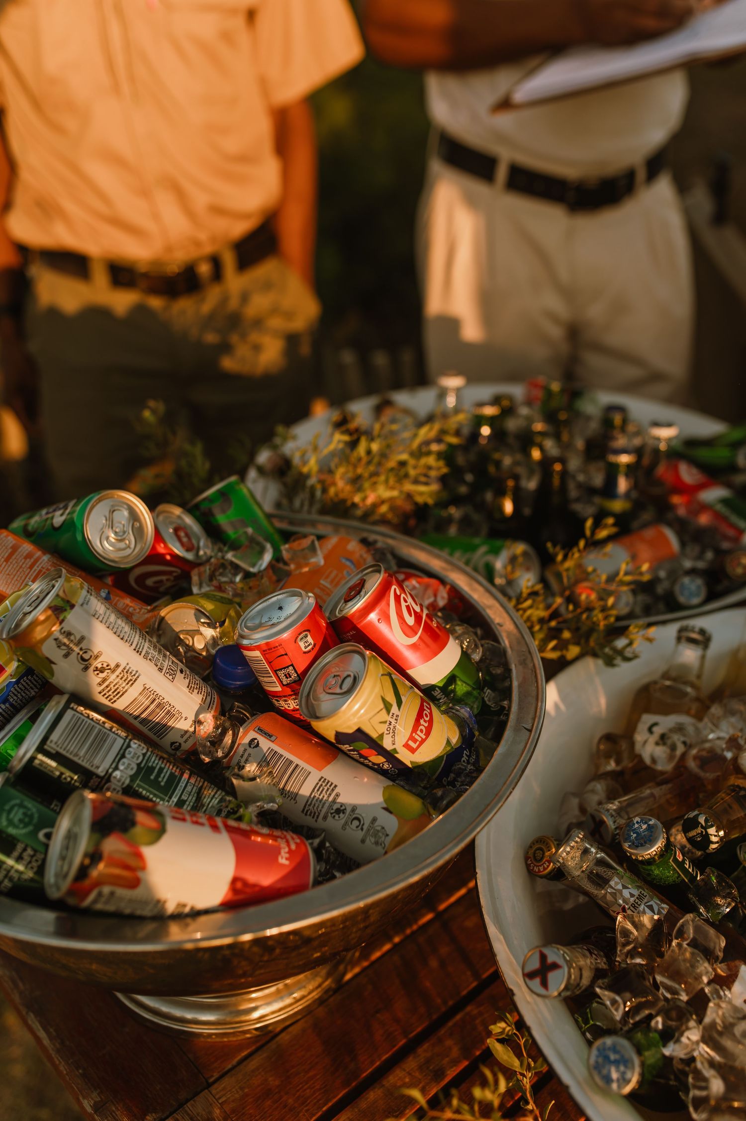 Assorted beverage cans and bottles arranged in metal containers with decorative elements.