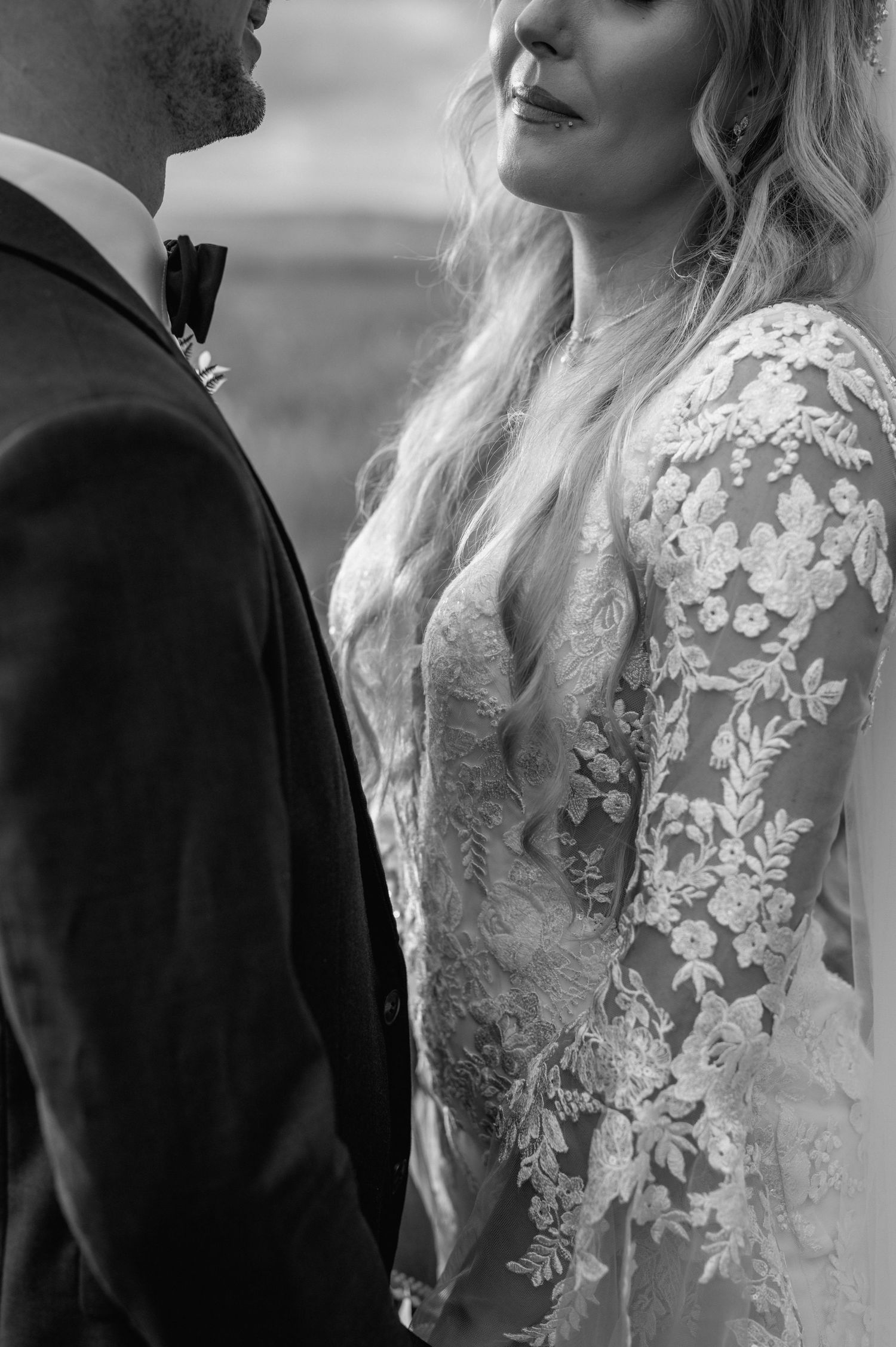 Black and white close-up of intricate lace details on a wedding dress.