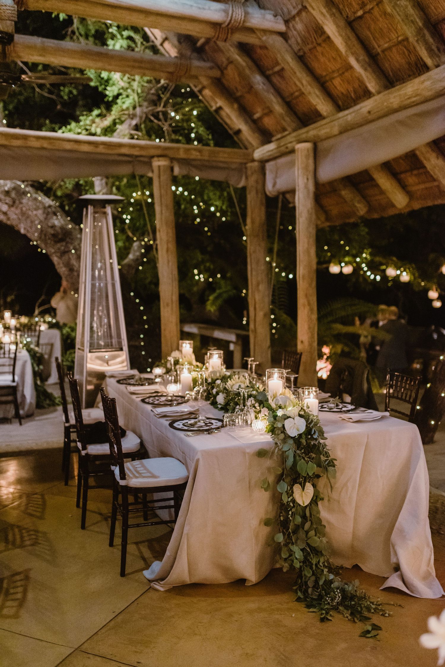 Rustic barn venue set up for wedding reception with white tablecloths and string lights.