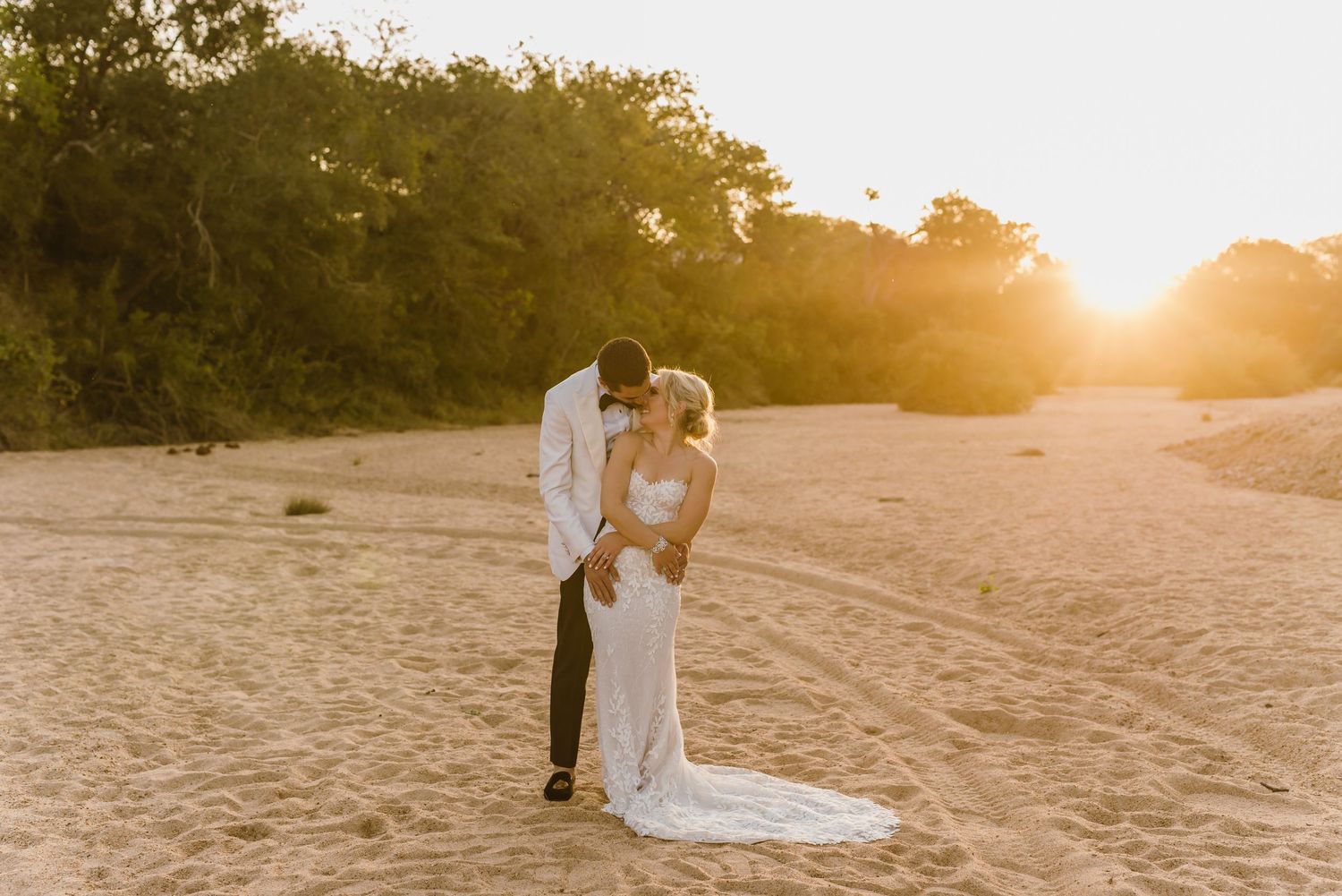 Bride and groom pose for romantic beach portraits at golden hour.