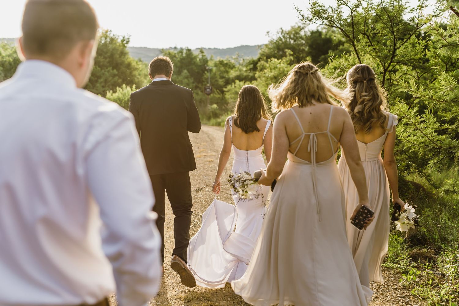 Wedding party walking down a nature path during golden hour.
