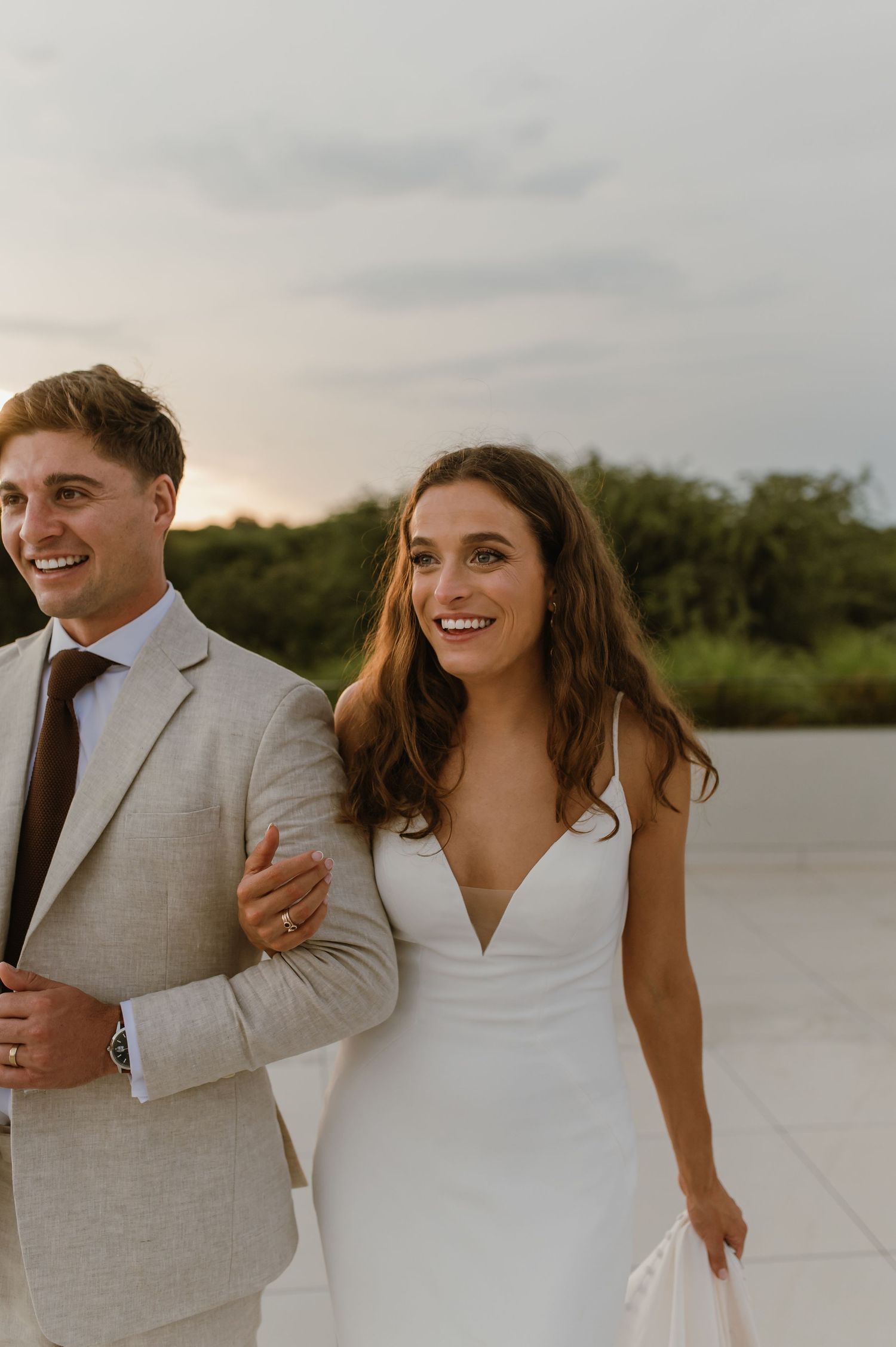 Happy wedding couple laughs together during outdoor portrait session by the water.