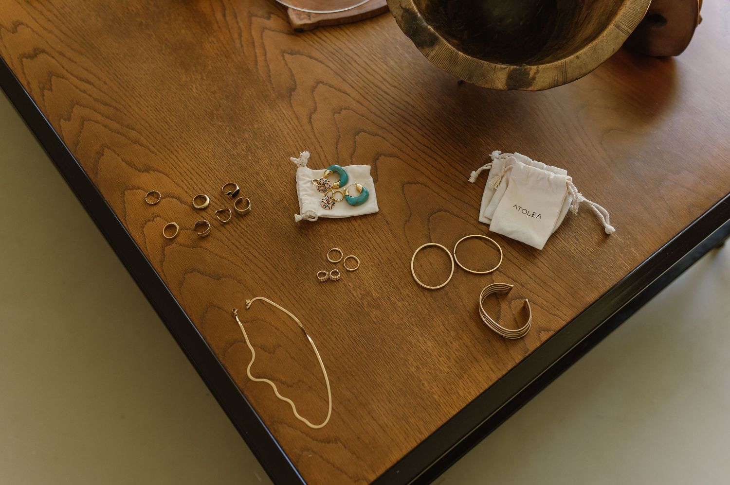 Collection of gold jewelry and accessories displayed on dark wooden surface.