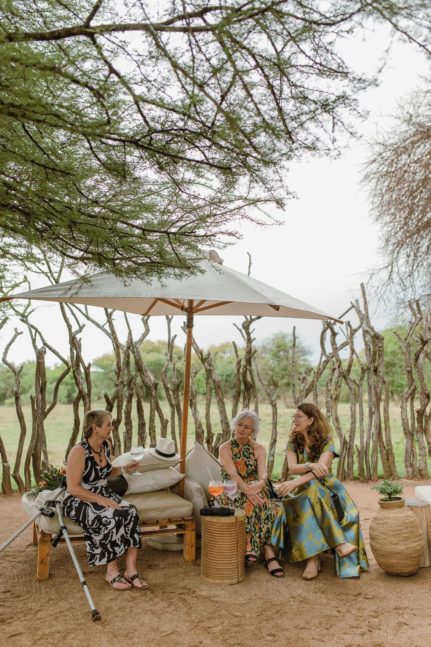 Outdoor seating area with umbrellas and guests relaxing under trees.