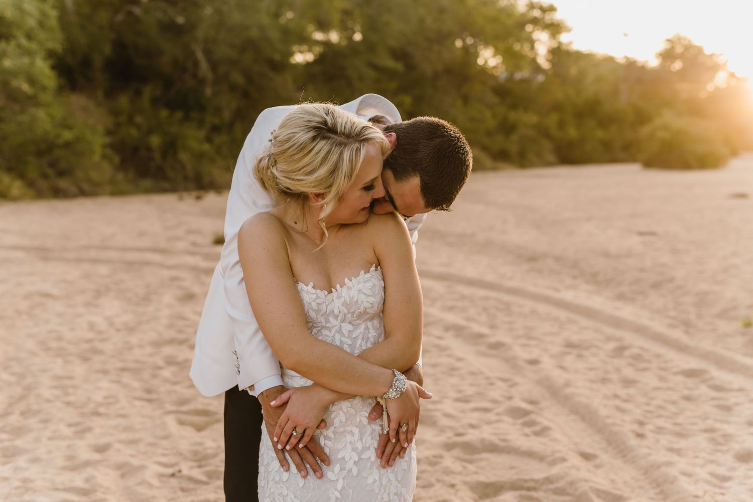 Wedding couple shares tender moments on sandy beach during sunset.