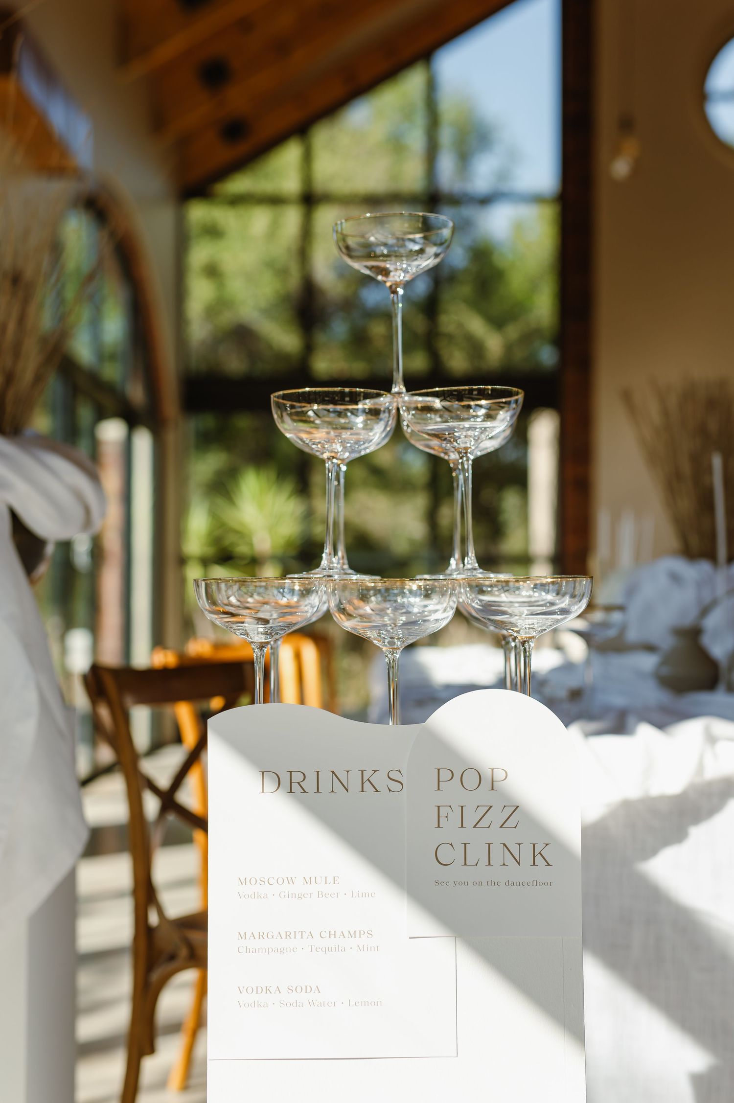 Elegant champagne glasses arranged on a sunlit table at a wedding reception.