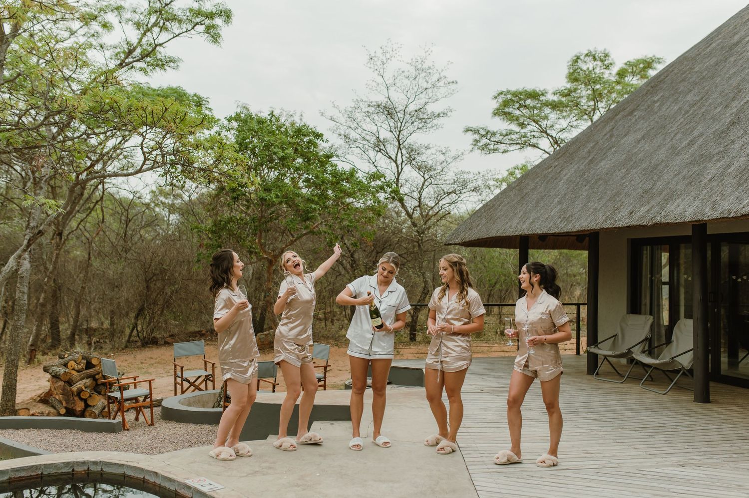 Group poses outdoors near rustic buildings in coordinated outfits.