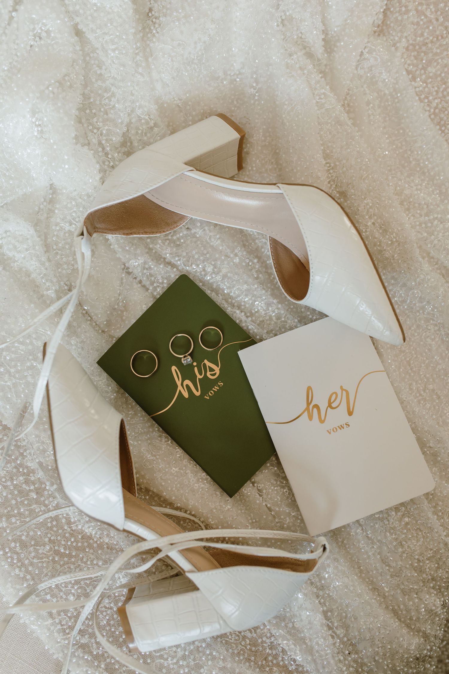Wedding invitation cards and envelopes in green and white colors scattered on a textured surface.