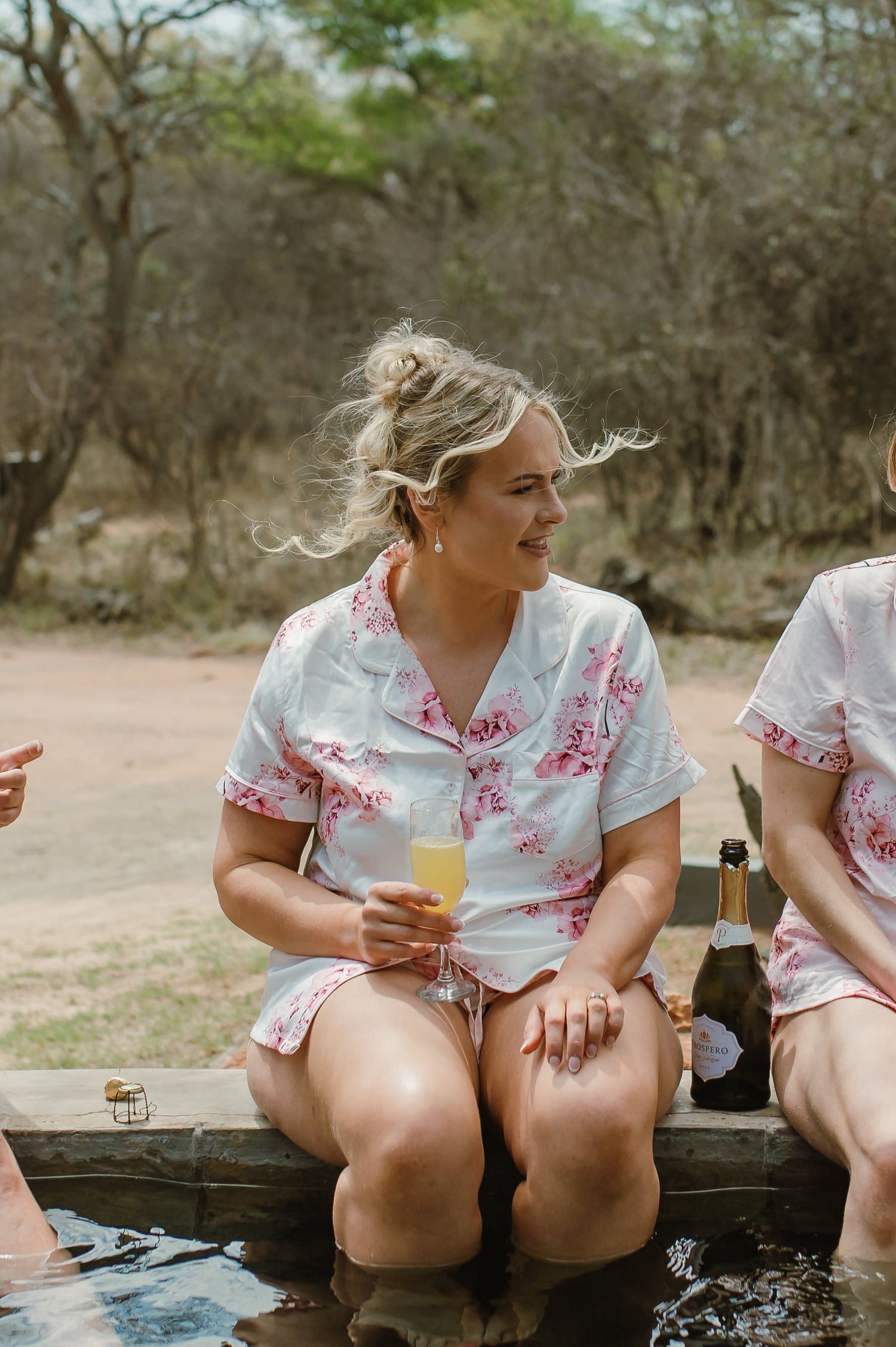 People in floral print outfits relaxing by a pool with drinks.