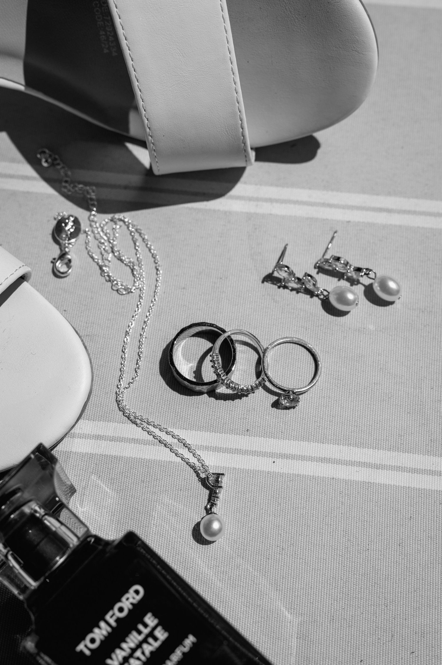 Wedding rings and jewelry photographed in dramatic black and white lighting.