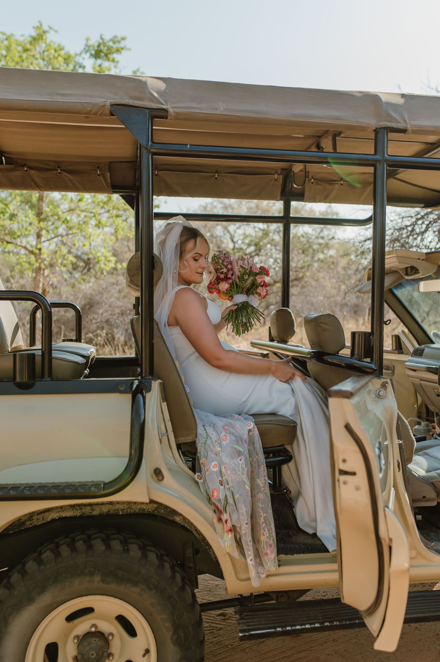 Safari vehicle interior decorated for a wedding with white dress visible.