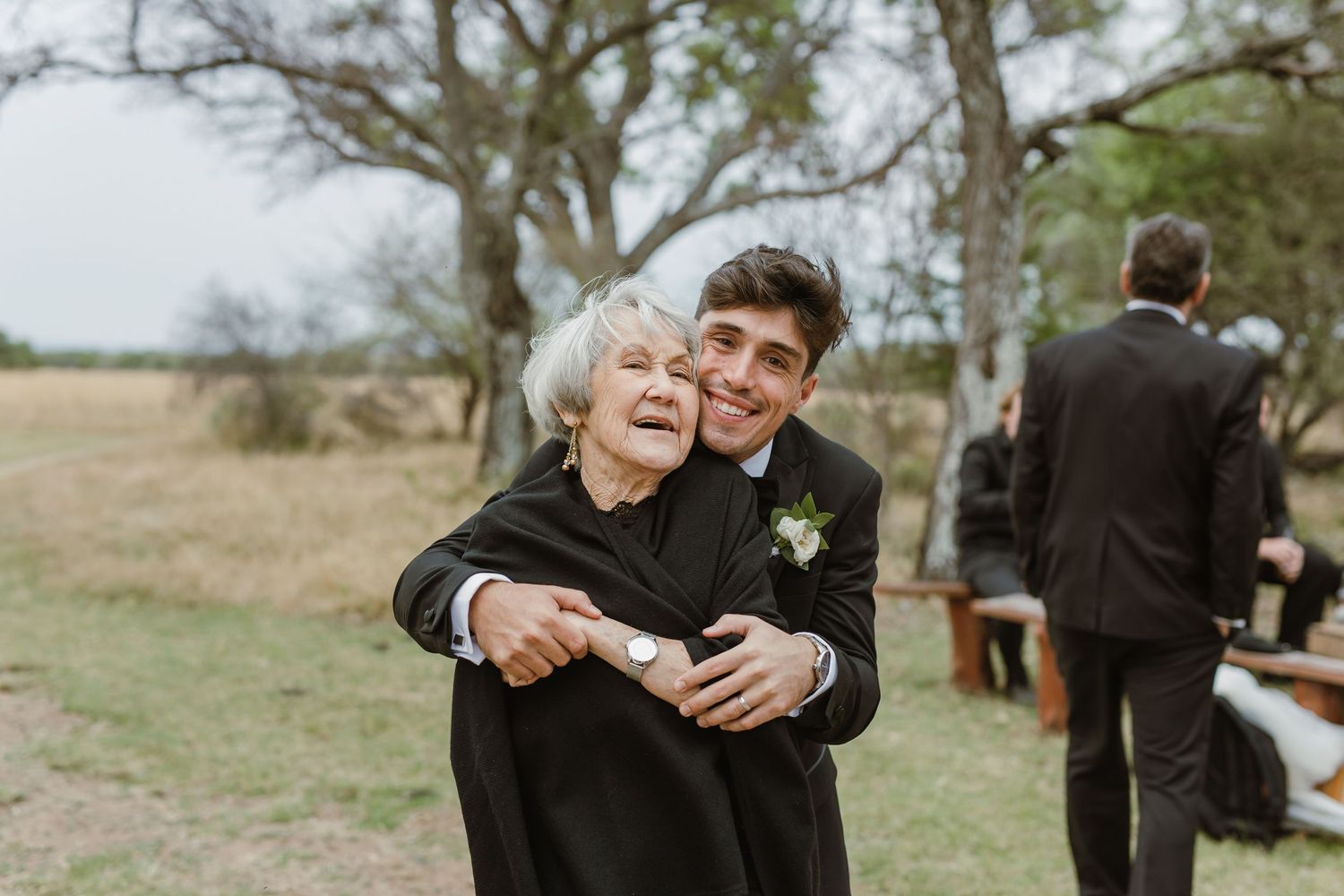 Wedding party embracing outdoors during a joyful celebration.