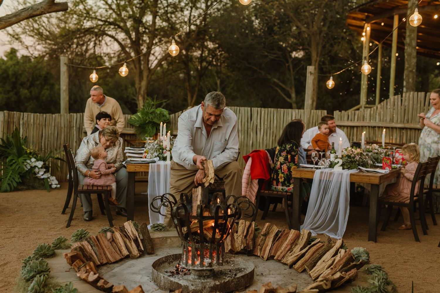 Outdoor wedding venue with wooden benches and string lights creating a romantic atmosphere.