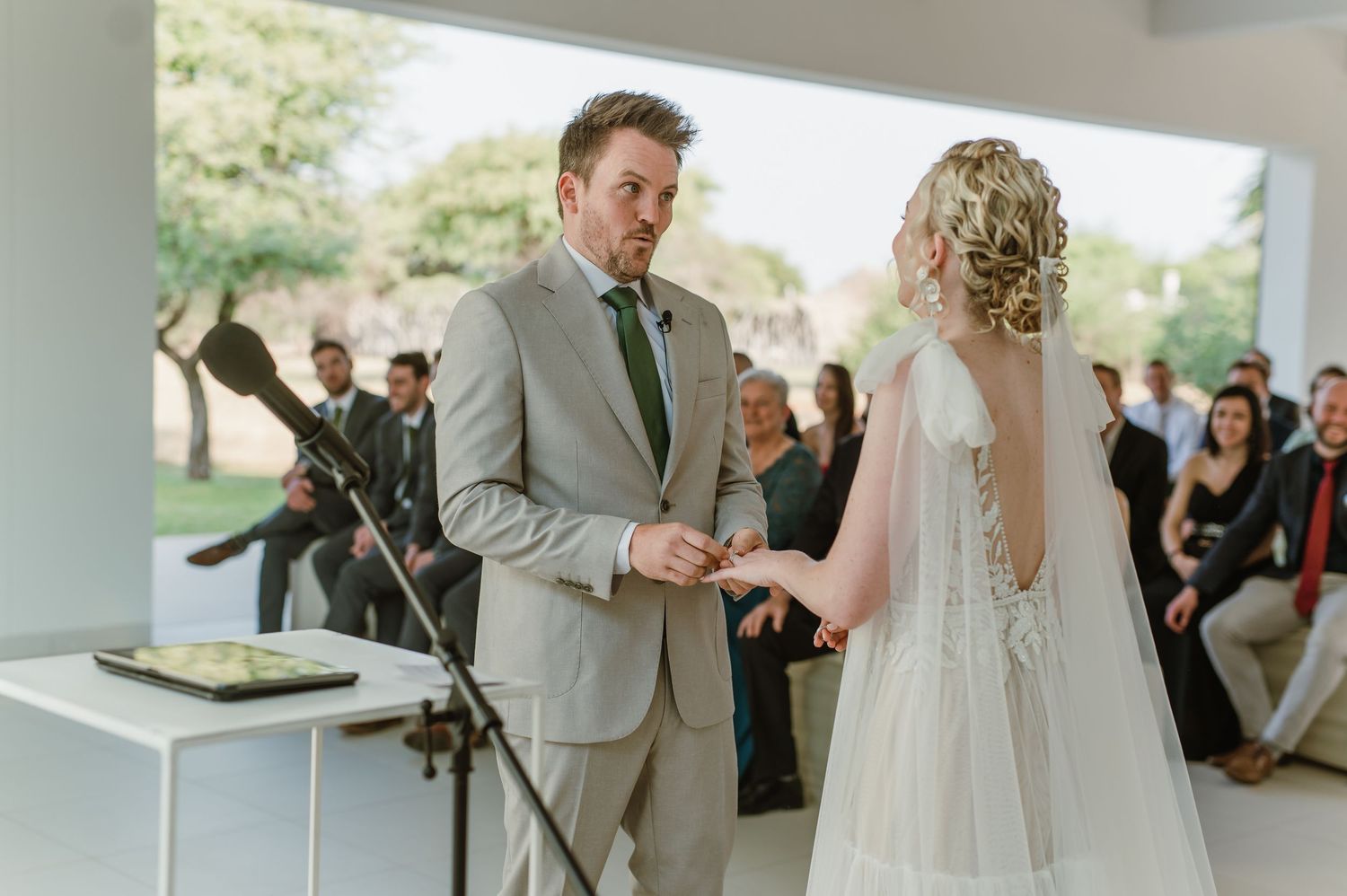 Couple exchanges vows during wedding ceremony in modern white venue.