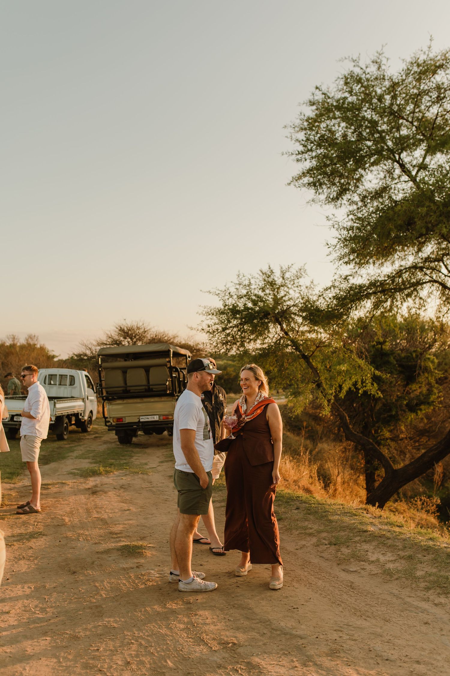 People gathered on a dirt path overlooking a scenic vista at sunset.