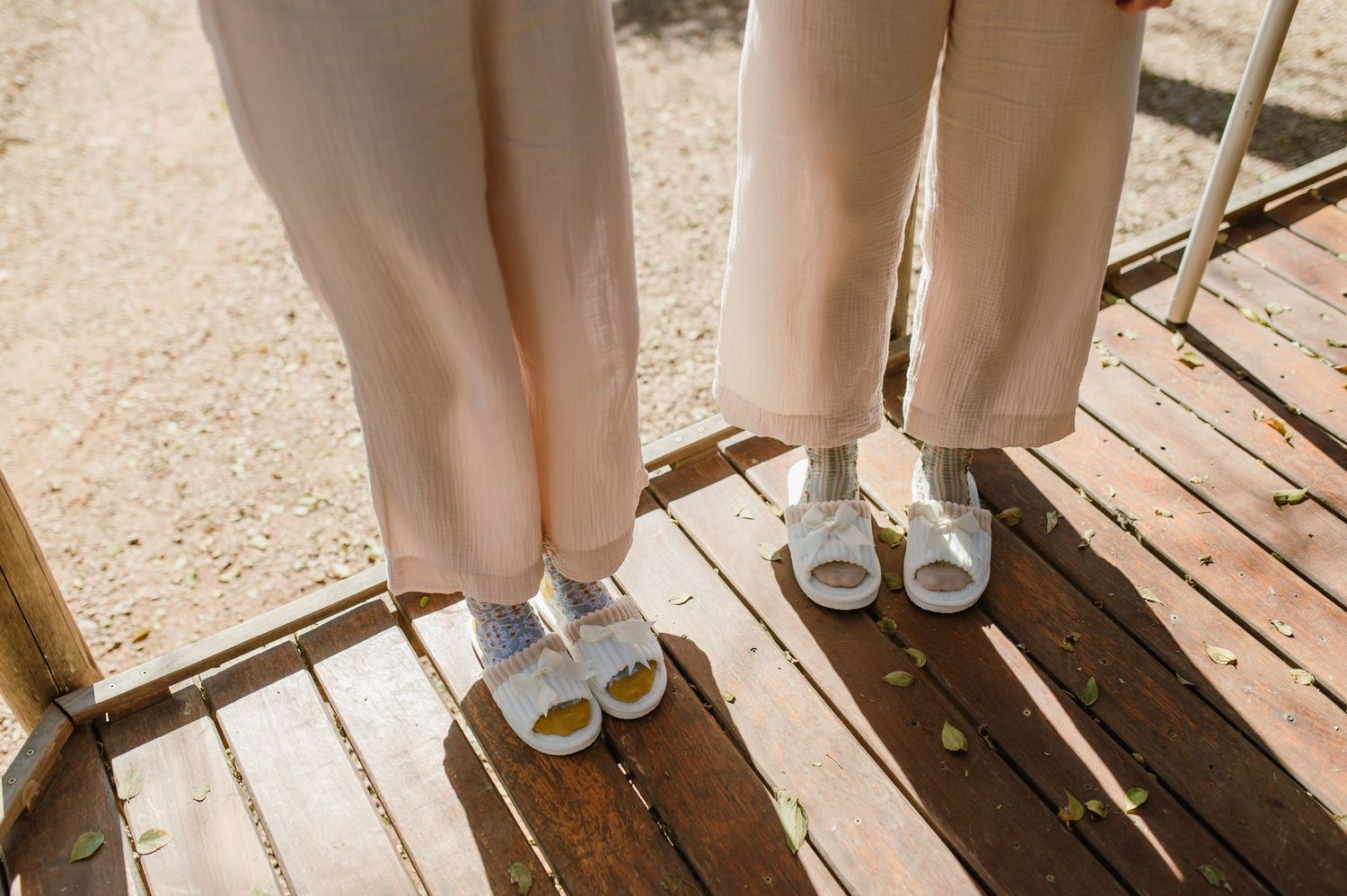 Lower body view of people standing on wooden deck wearing formal attire and shoes.