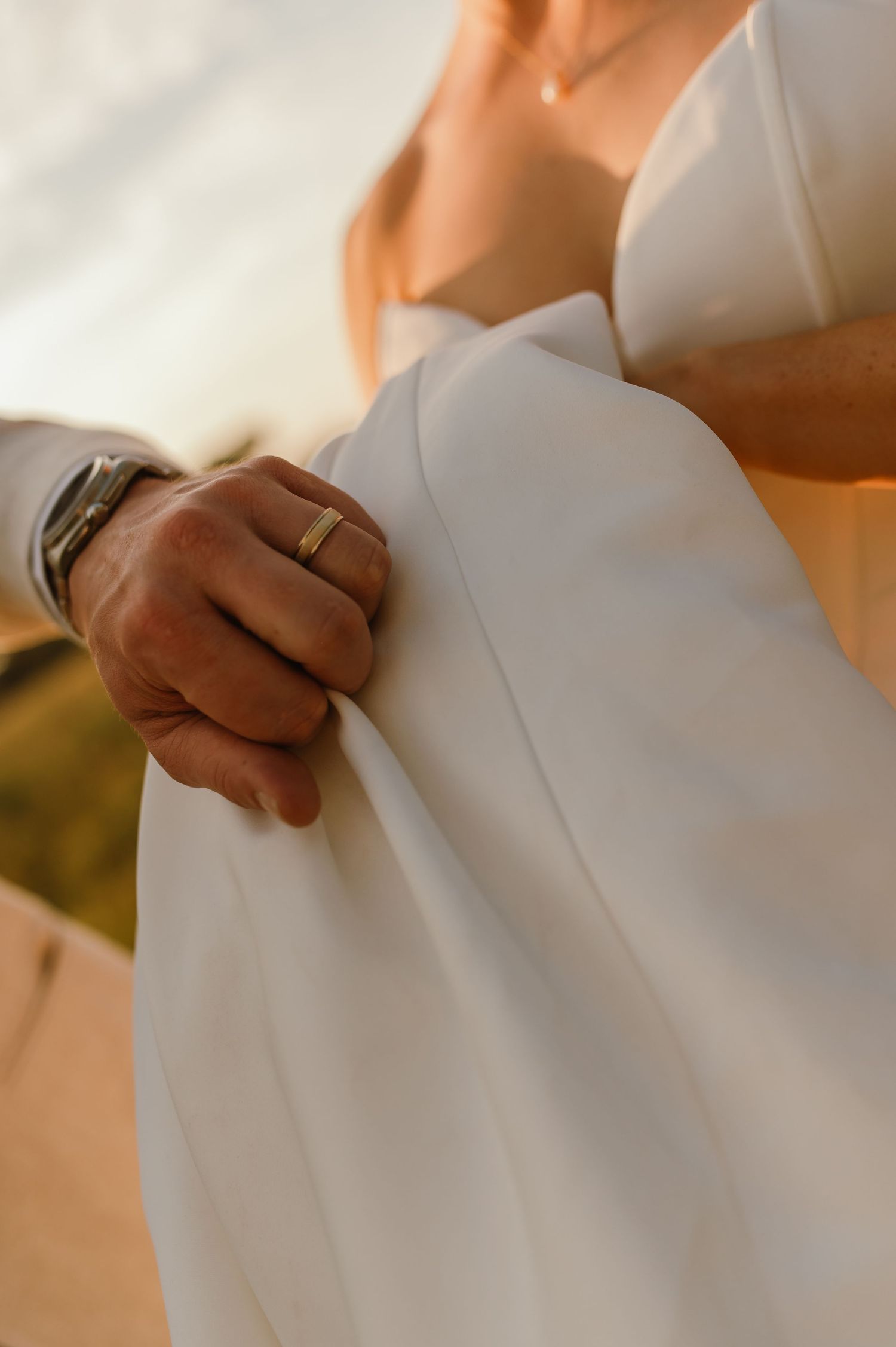 Close-up details of a pristine white wedding dress fabric in warm sunlight.