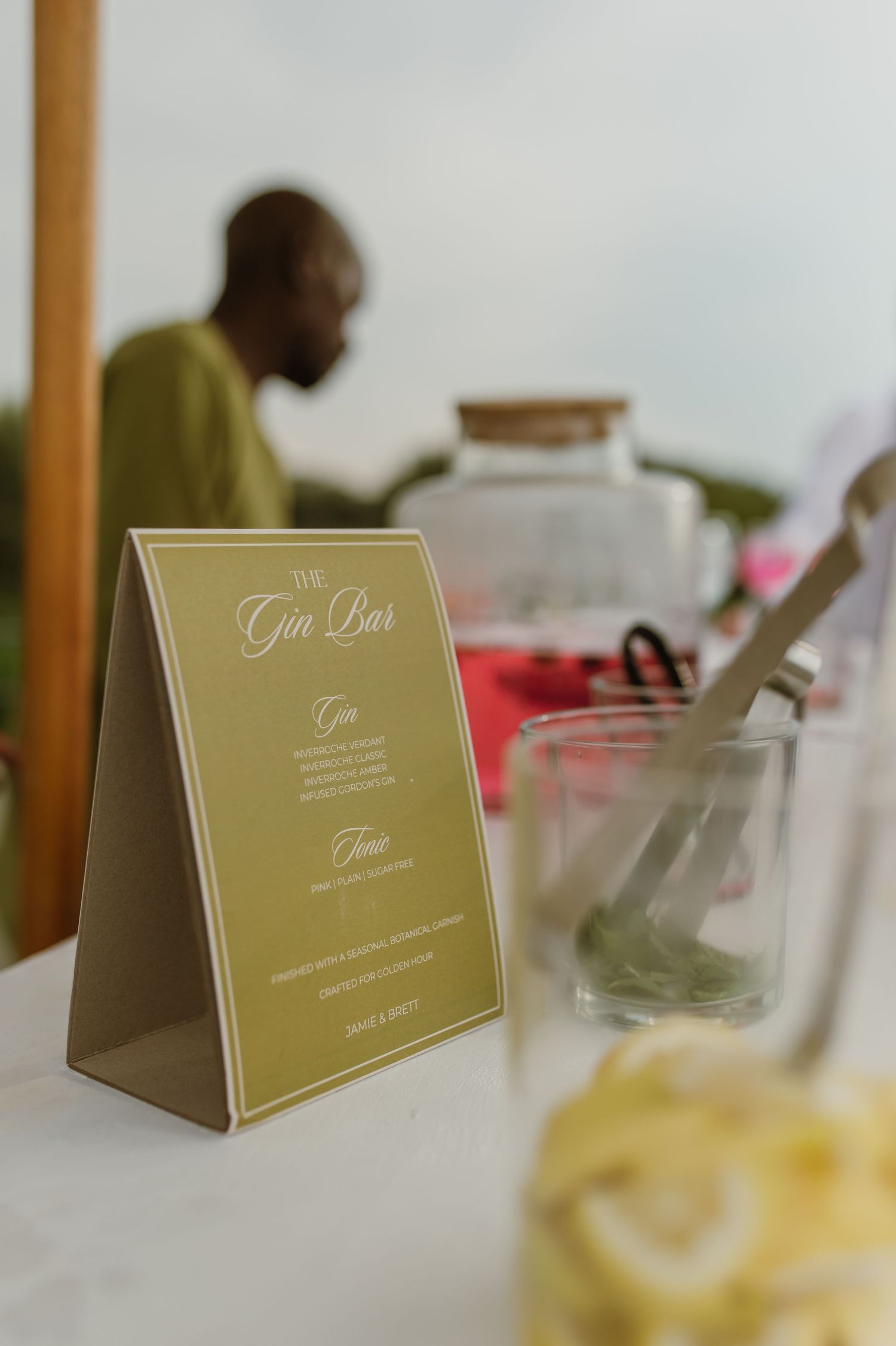 Wedding reception table settings with elegant gold name cards and table numbers displayed on white linens.