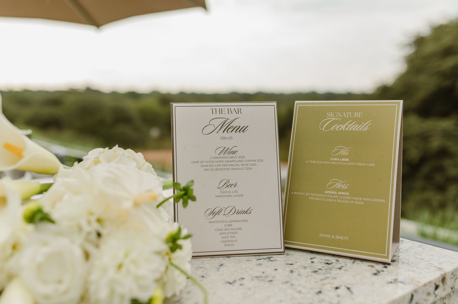 Elegant place cards and white floral arrangements displayed at a wedding reception.
