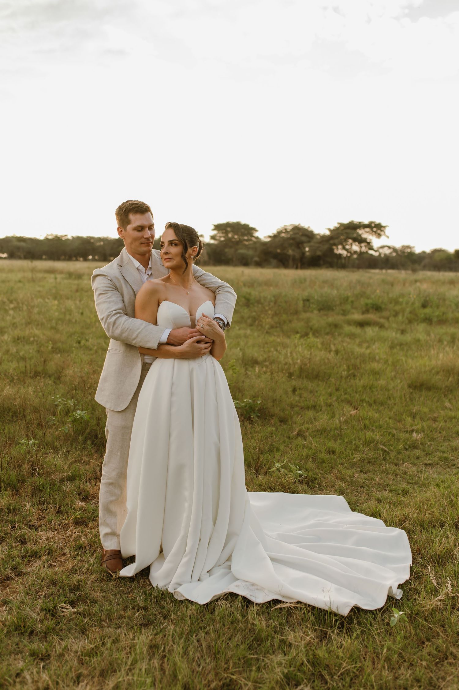Romantic sunset wedding photos of couple embracing in a golden field.