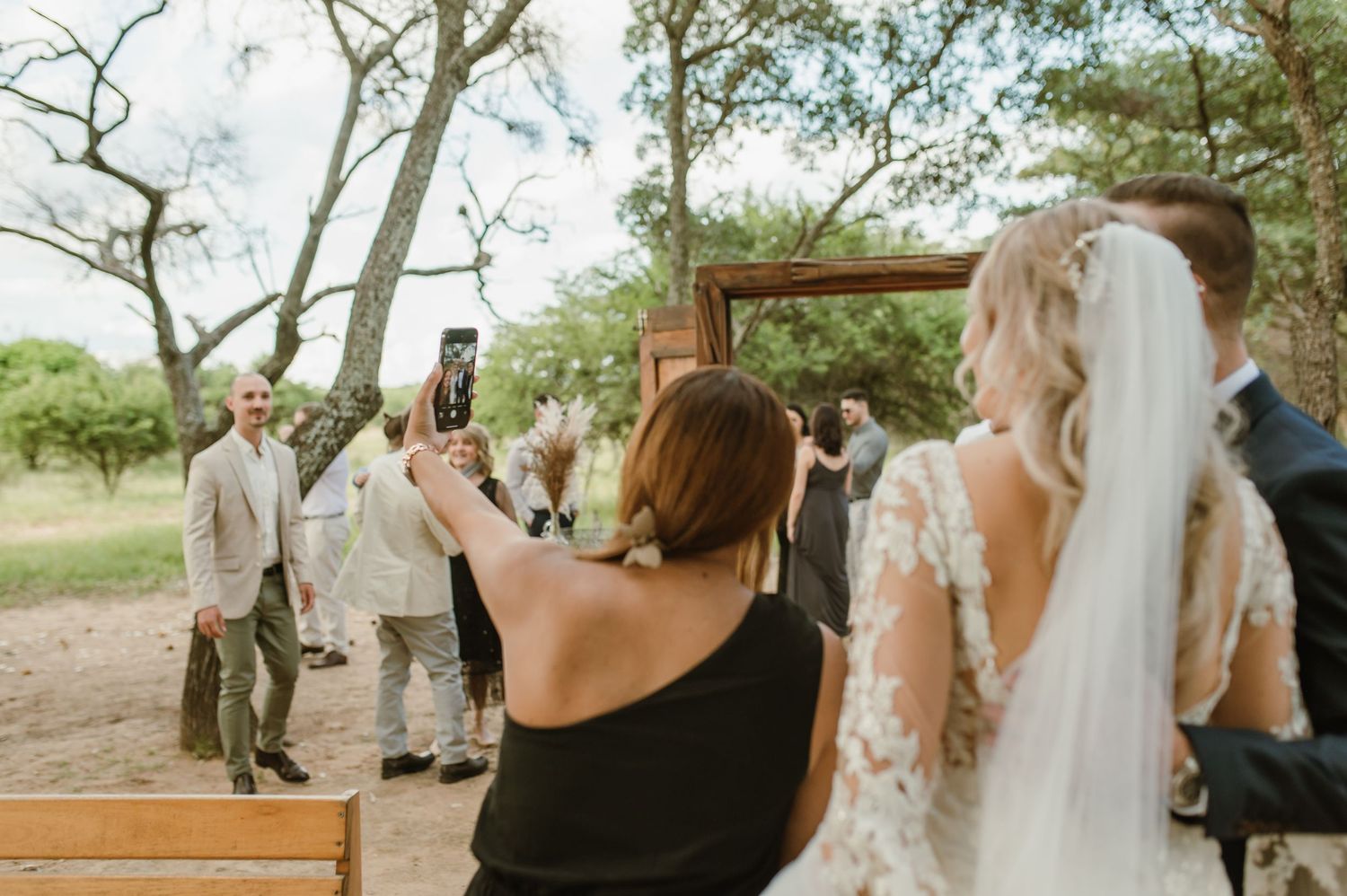 Natural outdoor wedding setting with wooden doors and tree backdrop.