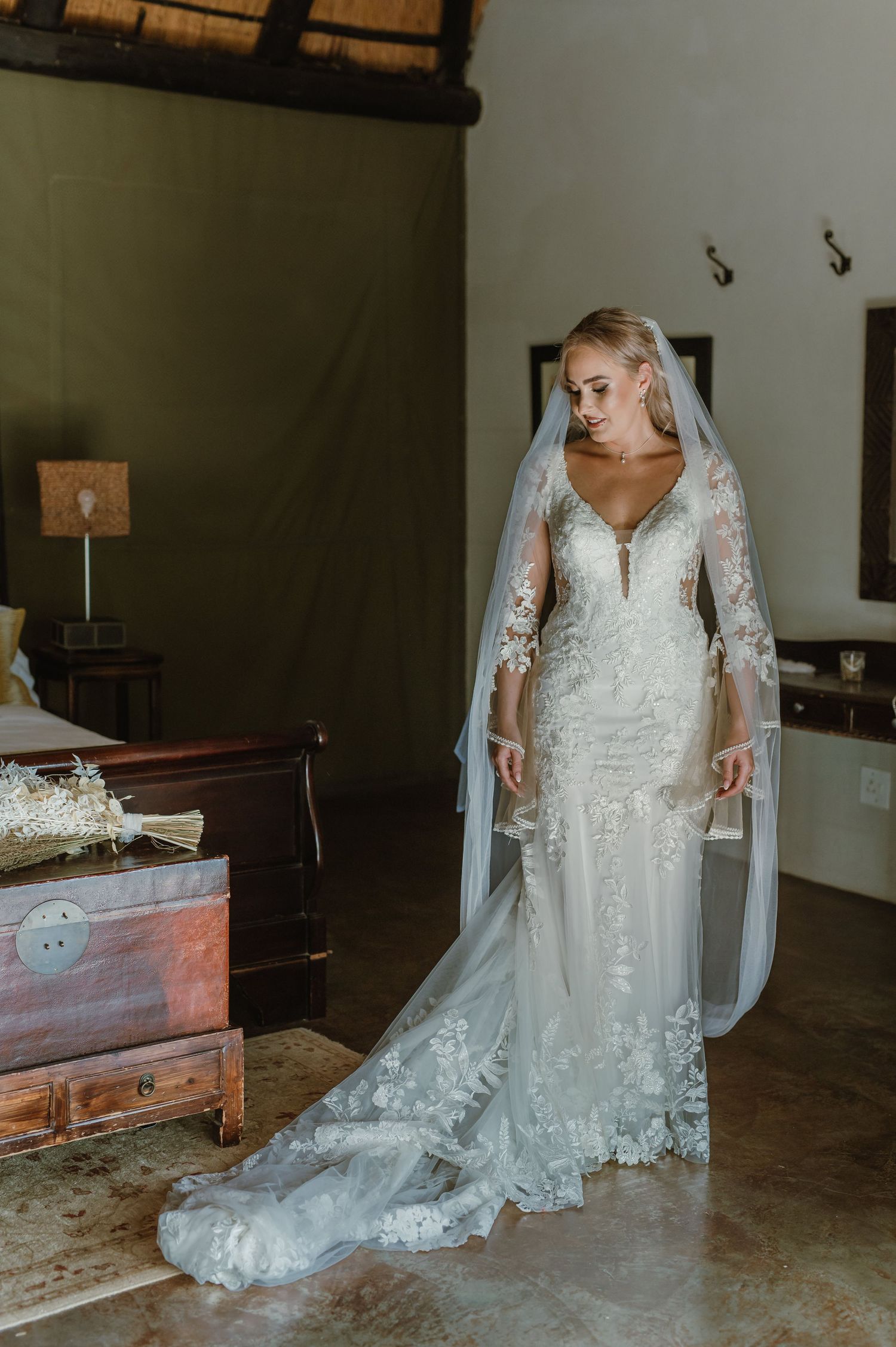 Full-length view of an elegant lace wedding dress with cathedral train in a rustic indoor setting.