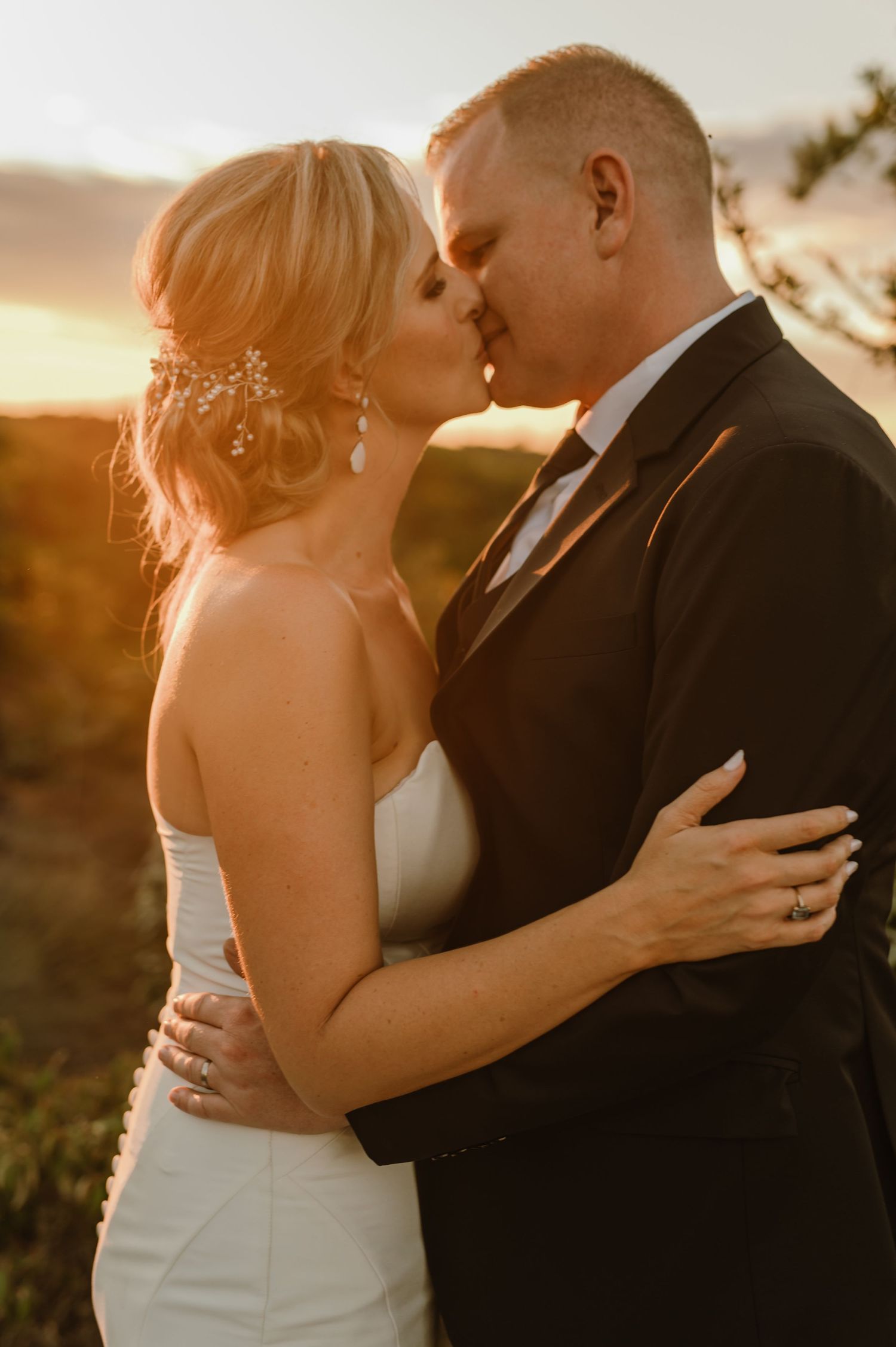 Intimate wedding portrait of a couple embracing during golden hour in a natural outdoor setting.
