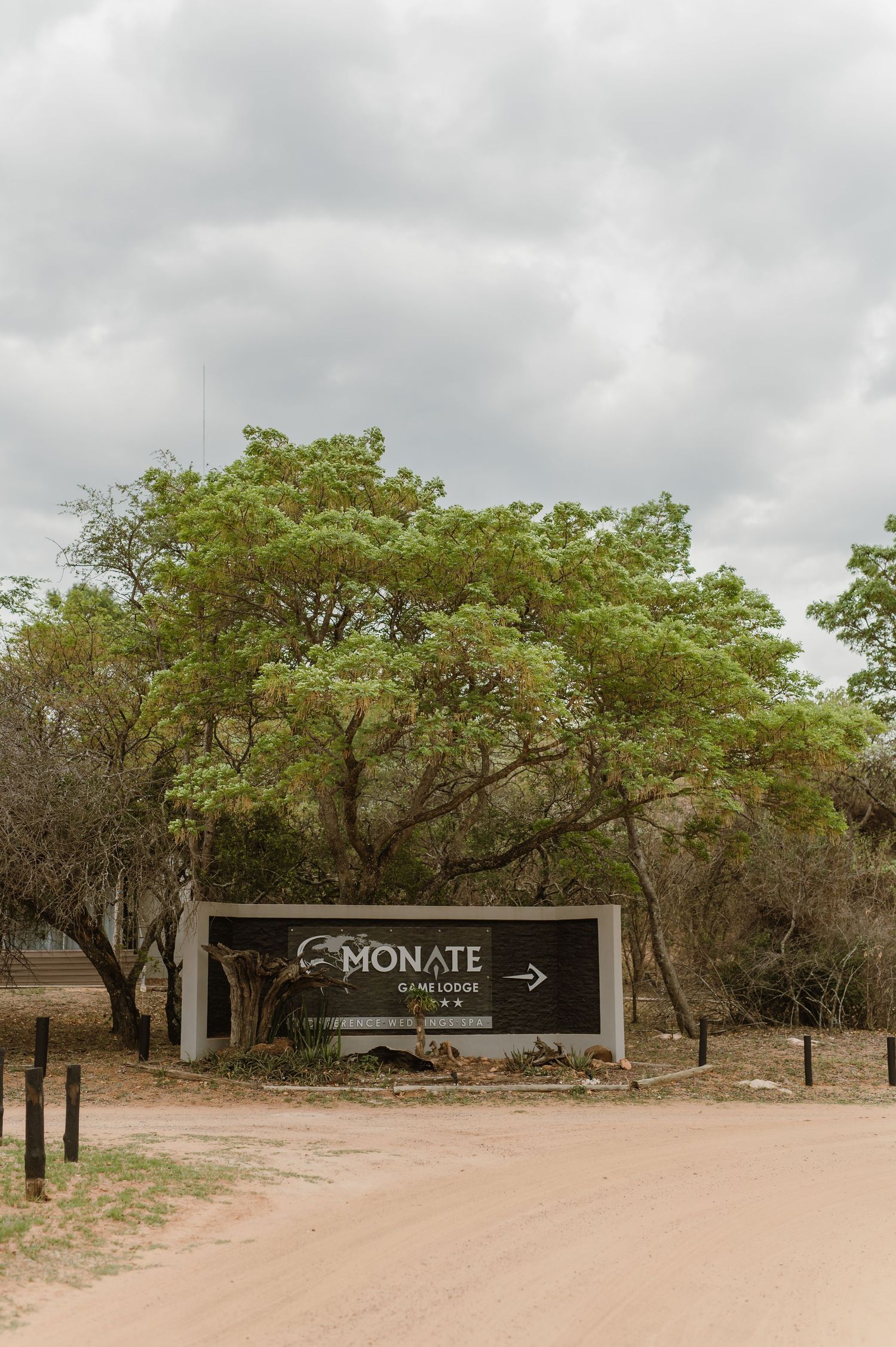A dirt road entrance with signage leading to Monate Game Lodge.