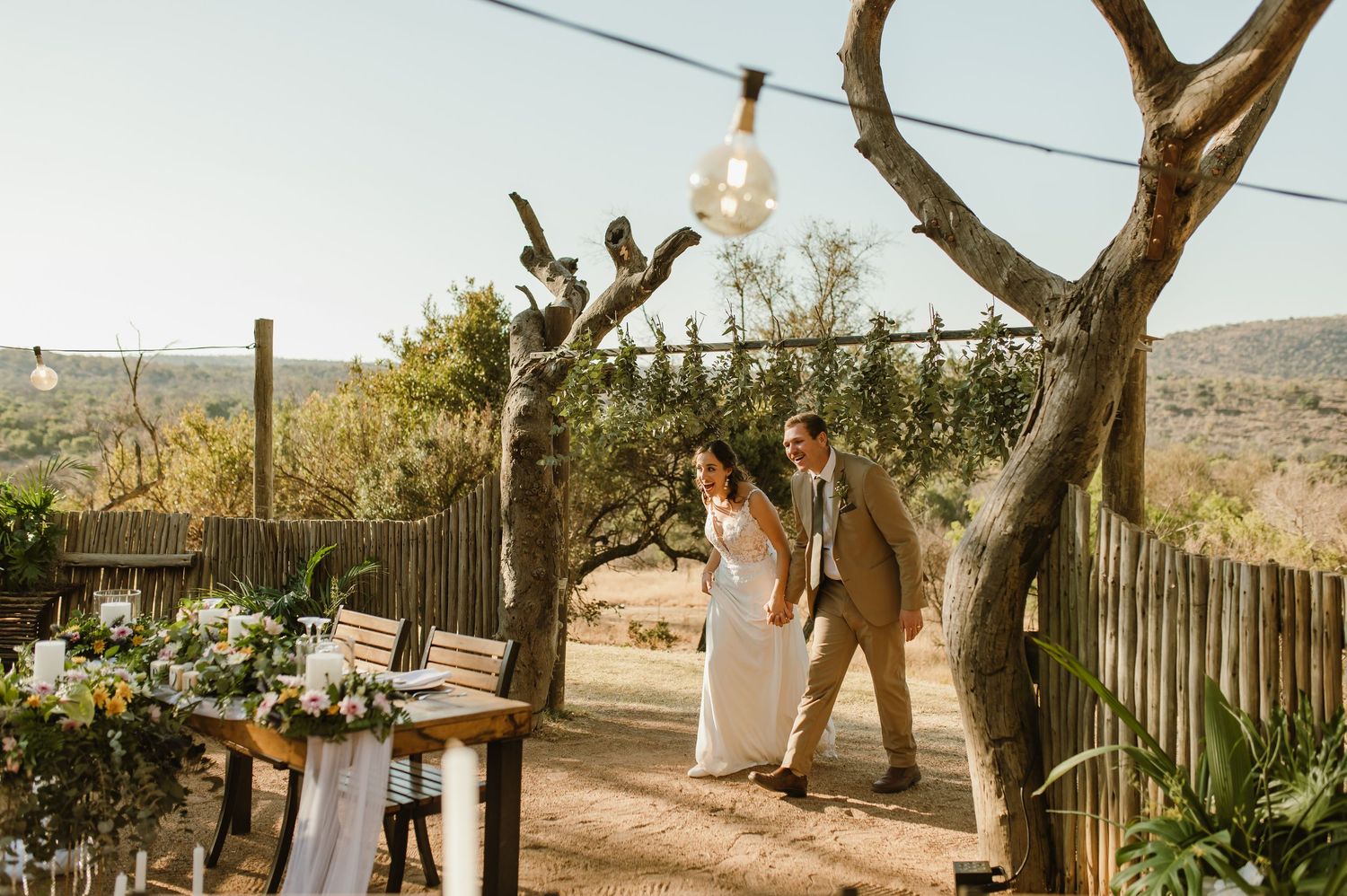 Outdoor wedding ceremony setup with wooden benches and natural decor against a desert landscape.