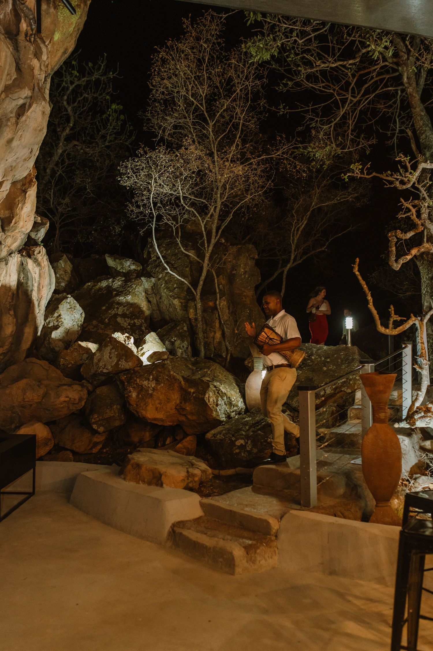 A candlelit cave setting with people seated on rock formations and steps.