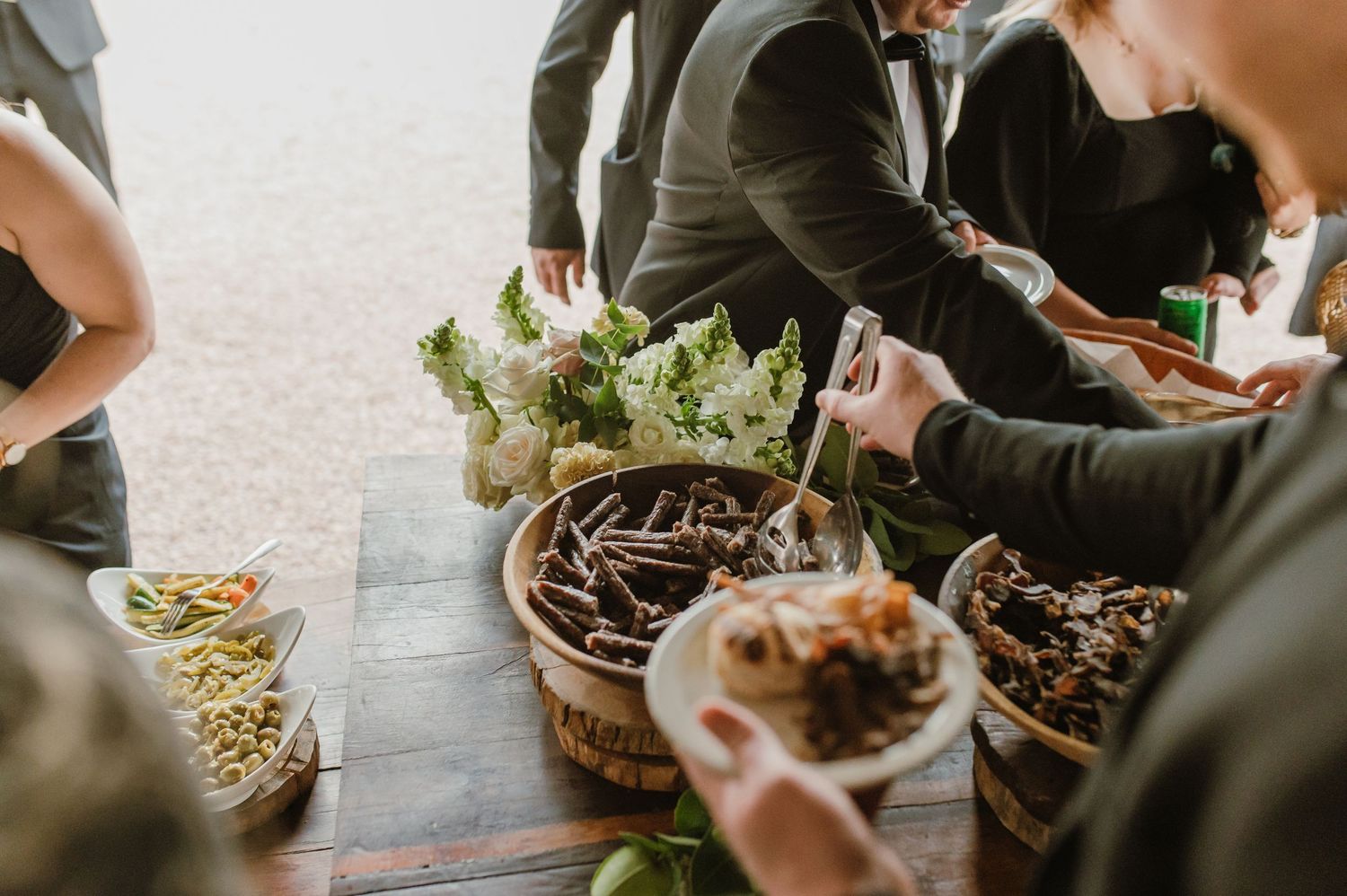 Close-up of wedding reception buffet with guests selecting food.
